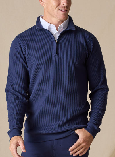 Men's Cambria Quarter Zip in New Indigo, front on-model view featuring a navy ribbed knit fabric with a quarter zip closure and navy interior collar, styled with navy pants
