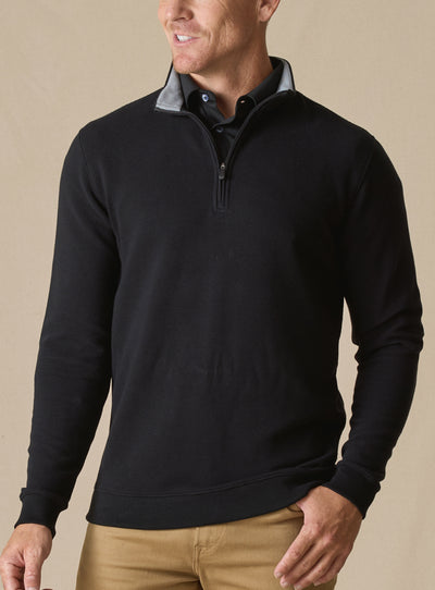 Men's Catalina Quarter Zip in Black, front on-model view featuring a black ribbed fabric with a quarter zip closure and gray interior collar, styled with tan pants