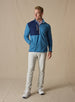 Men's Moonstone Quarter Zip in Petrol, full-length front model view featuring a medium blue micro-fleece body with navy contrast chest panel, styled with stone pants and white shoes against a neutral canvas backdrop