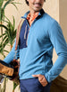 Men's Moonstone Quarter Zip in Petrol, lifestyle front model view featuring a medium blue micro-fleece body with navy contrast chest panel and orange zipper tape, layered over an orange polo, styled with navy pants while carrying a vintage leather golf bag