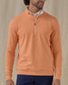 Men's Patron Quarter Zip in Citrus, front view on model featuring a solid peach orange body with a quarter zip neckline, paired with navy pants