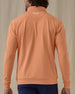 Men's Patron Quarter Zip in Citrus, back view on model featuring a solid peach orange body with a Straight Down logo embroidered at the upper back, paired with navy pants