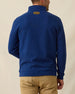 Men's Montecito Quarter Zip in New Indigo, back view on model featuring a ribbed knit texture with tan Straight Down leather patch at center back neck, layered over a white polo, paired with khaki pants