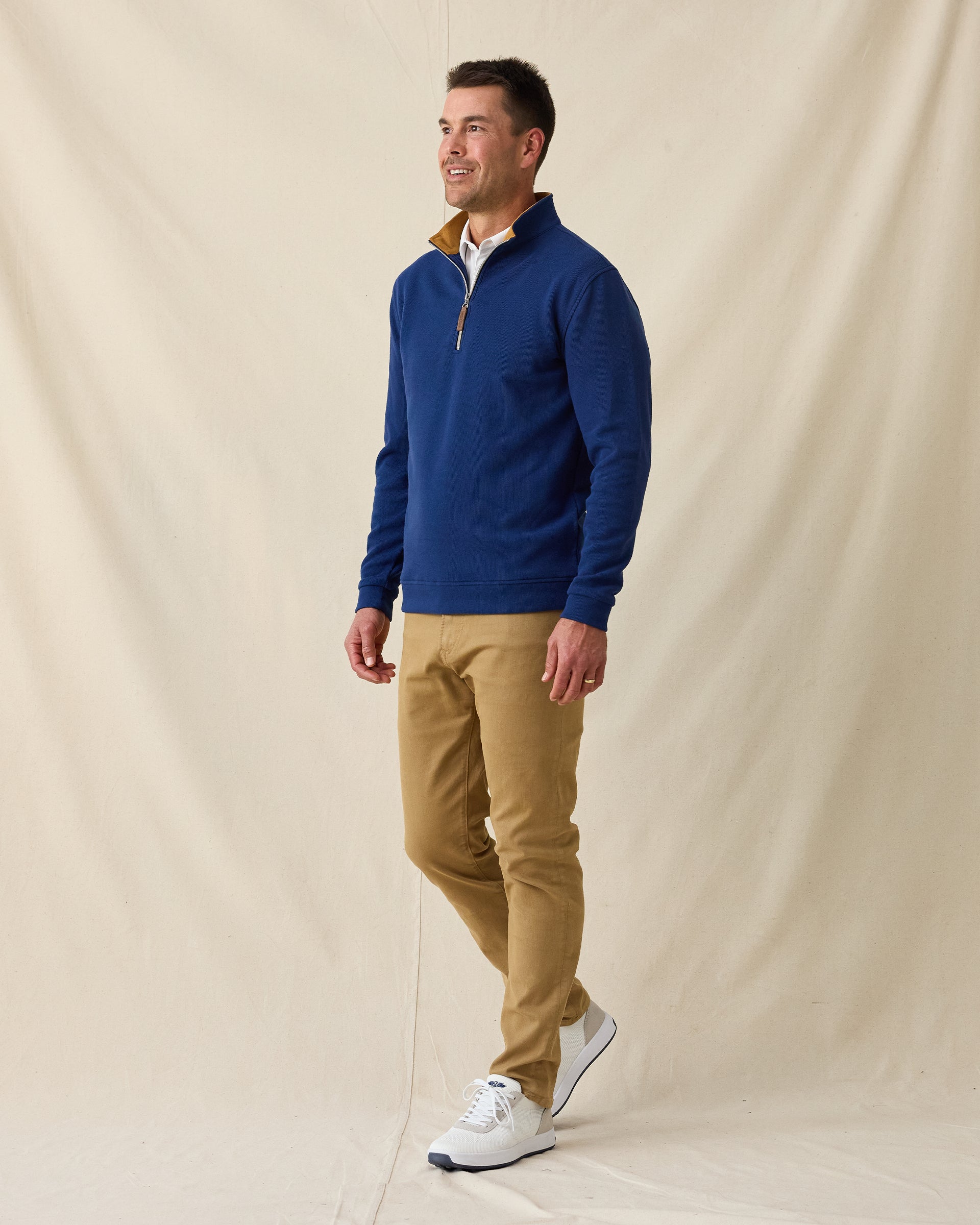 Men's Montecito Quarter Zip in New Indigo, full length front view on model featuring a ribbed knit texture with tan suede collar lining and silver zipper, layered over a white polo, paired with khaki pants and white shoes