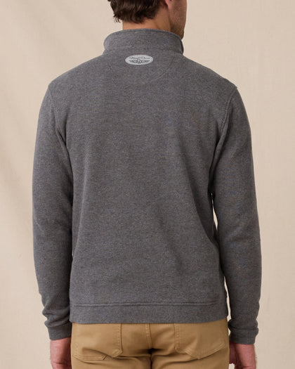 A model viewed from the back wearing a dark heather gray quarter-zip pullover sweater and tan pants, against a plain beige studio background.