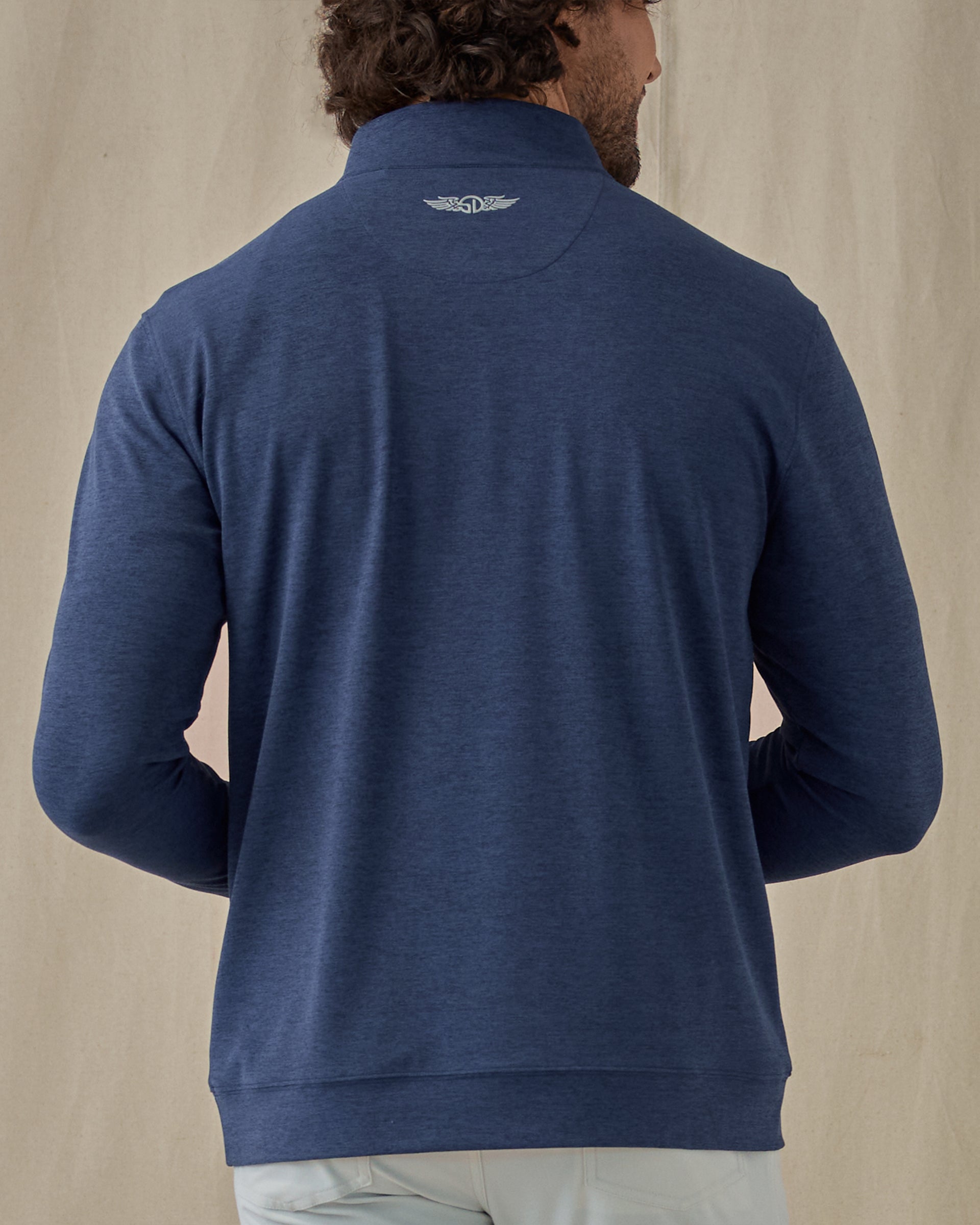 Men's Tiburon Quarter Zip in New Indigo, back view on model featuring a solid heathered navy body with a Straight Down logo embroidered at the upper back, paired with light gray pants