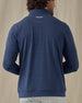 Men's Tiburon Quarter Zip in New Indigo, back view on model featuring a solid heathered navy body with a Straight Down logo embroidered at the upper back, paired with light gray pants