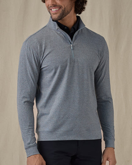 Men's Tiburon Quarter Zip in Storm, front view on model featuring a heathered gray solid fabric with a quarter zip placket and mock neck collar, layered over a black polo, paired with black pants