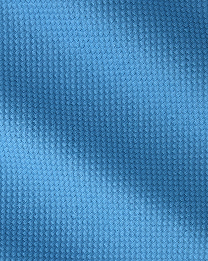 A close-up of a textured blue fabric with a fine, repeating waffle or mesh-like pattern.