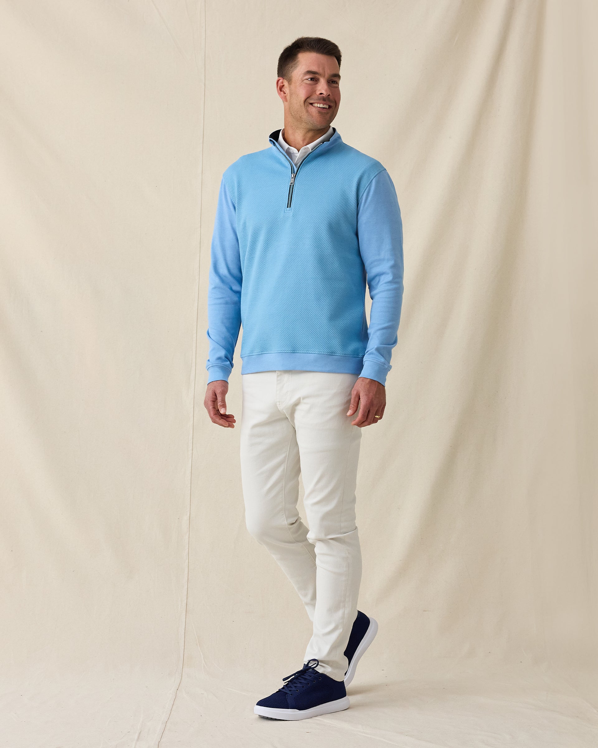 Men's Cardiff Quarter Zip in Coastal, full length model view featuring a medium blue long sleeve quarter zip pullover with a textured waffle-knit front panel and navy contrast zip placket, layered over a white polo, styled with white pants and navy shoes