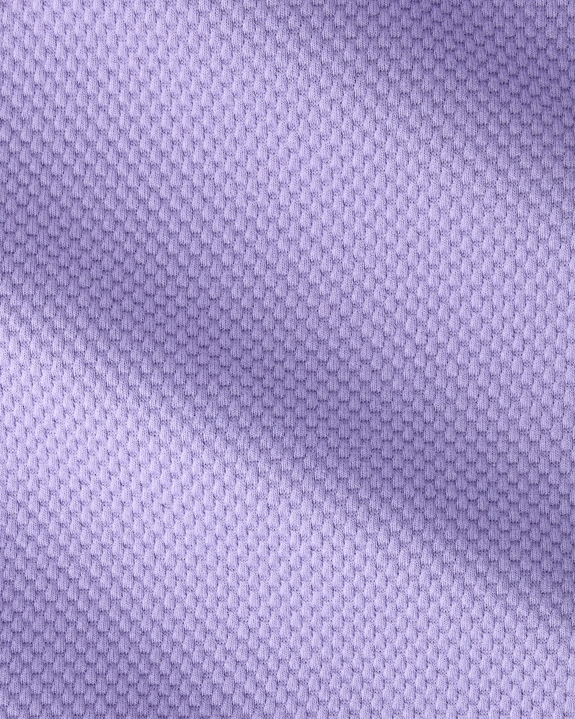 A close-up of a light purple textured fabric with a fine woven pattern and soft diagonal shadows.