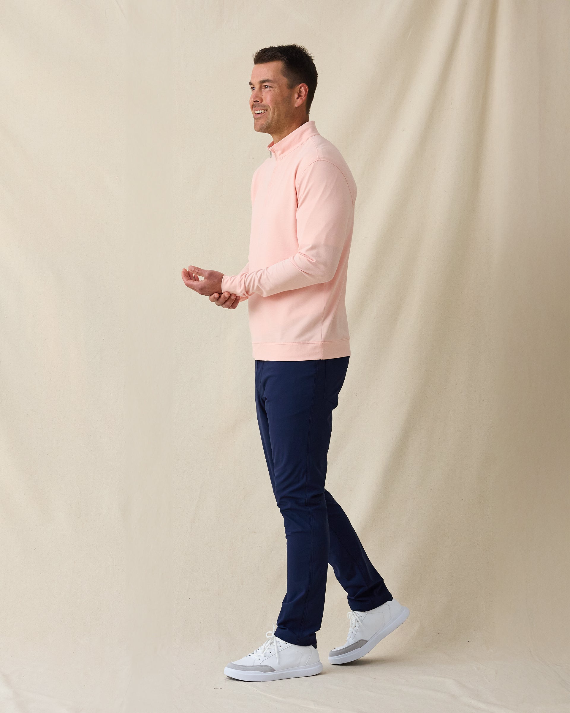 Men's Palmetto Quarter Zip in Spritz, side model view featuring a light pink long sleeve quarter zip pullover with a smooth performance fabric, styled with navy pants and white shoes