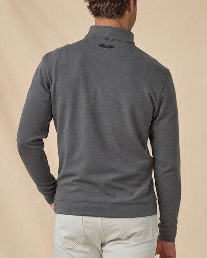 Back view of model wearing the Warren Quarter Zip in Black, showing the textured knit, banded hem, and embroidered logo below the collar.