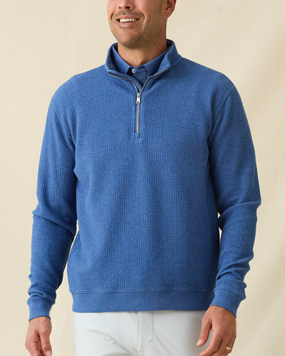 Men's Topanga Quarter Zip in Moonlight, front view on model featuring a bubble knit texture with silver zipper, layered over a blue polo, paired with white pants