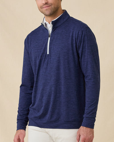 Front view of a male model wearing the Palmer Quarter Zip in New Indigo over a white polo with light-colored pants.