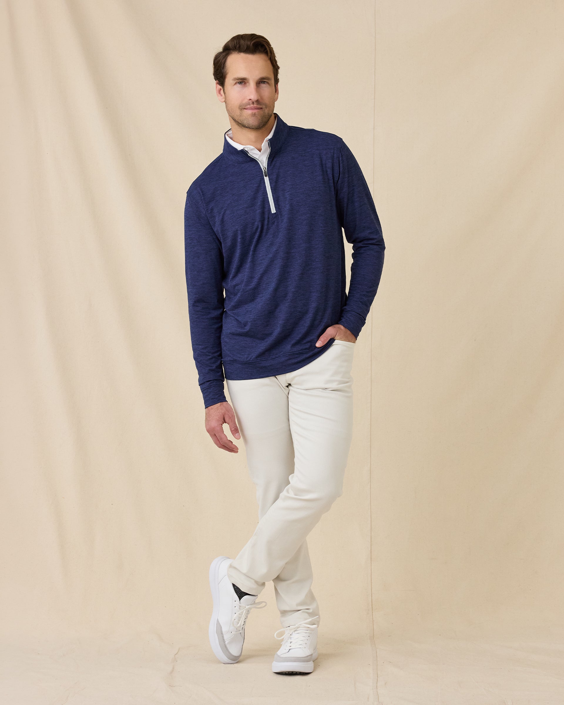 Full-length view of a male model wearing the Palmer Quarter Zip in New Indigo with light-colored pants and white shoes.