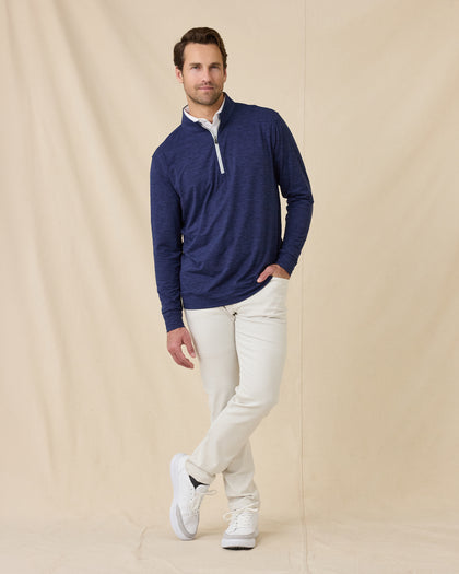 Full-length view of a male model wearing the Palmer Quarter Zip in New Indigo with light-colored pants and white shoes.