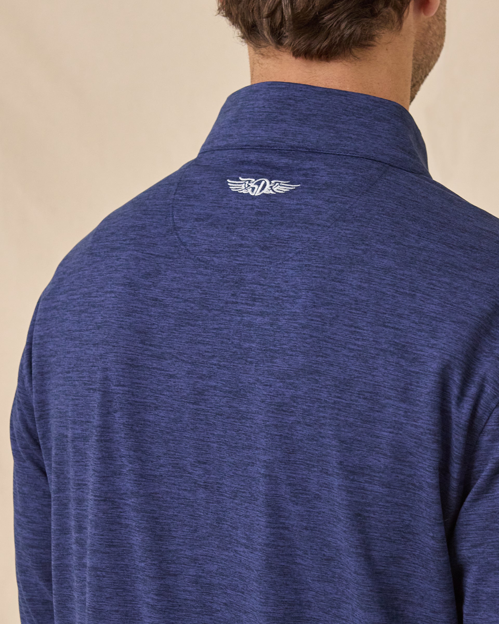 Close-up back view of the Palmer Quarter Zip in New Indigo, highlighting the heathered fabric and embroidered logo below the collar.