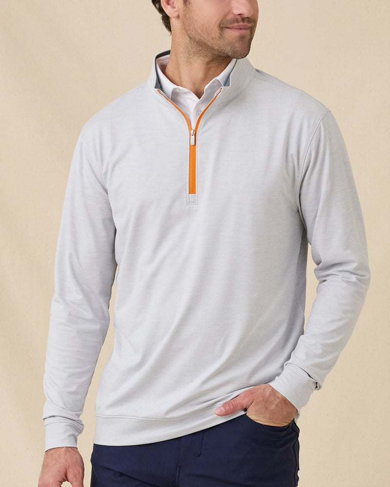 Model wearing the Palmer Quarter Zip in Heather over a white polo, showing the light heathered fabric and contrasting orange quarter-zip detail.