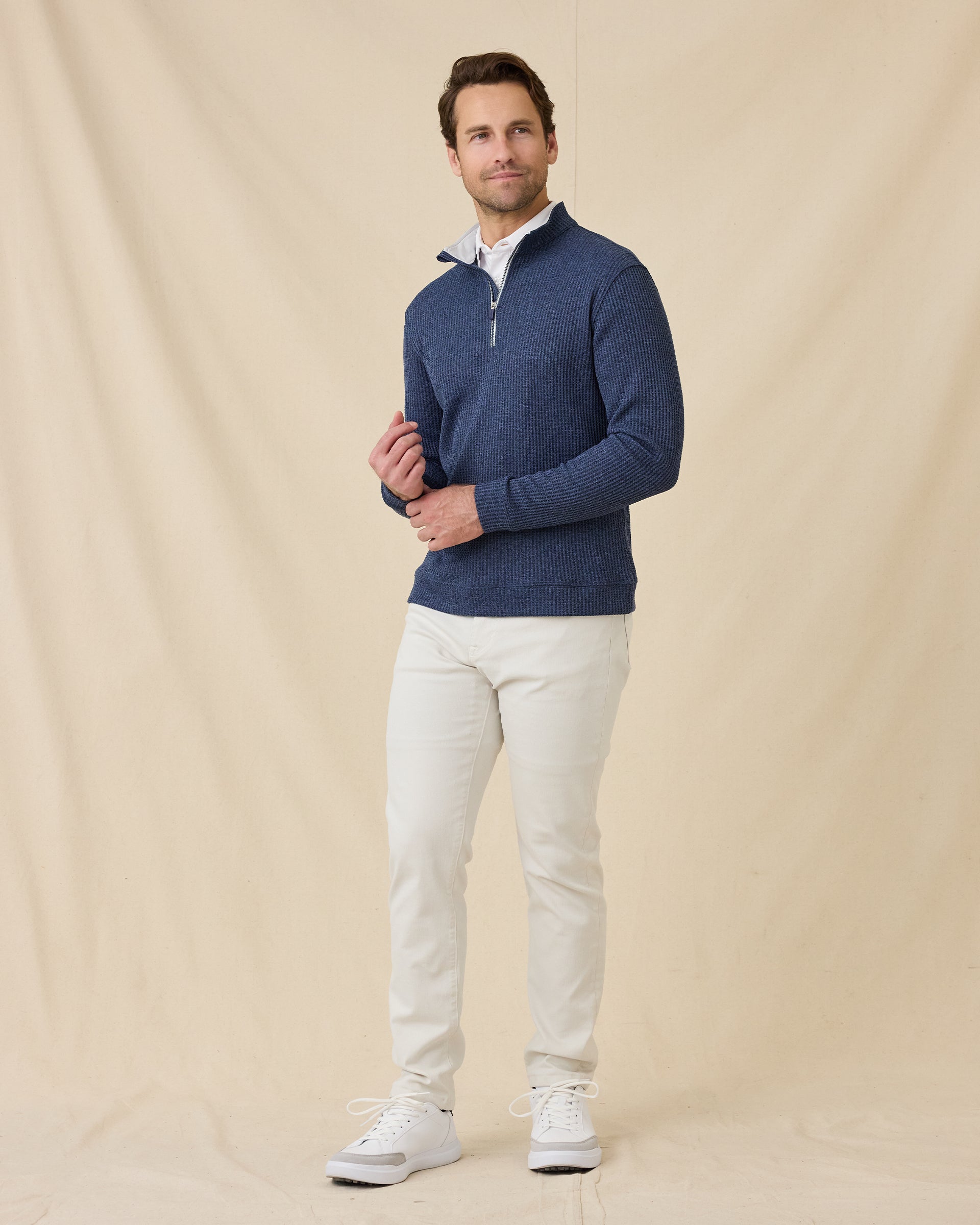 Full-length view of a male model wearing the Huntington Quarter Zip in New Indigo with white pants and white shoes.