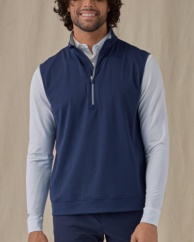 Men's Carson Vest in New Indigo, on model front view highlighting the navy body with grey quarter zip and grey collar interior layered over a white long sleeve top