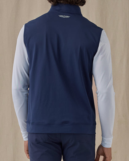 Men's Carson Vest in New Indigo, on model back view showing the Straight Down logo at the upper back layered over a white long sleeve top