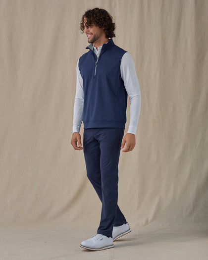 Men's Carson Vest in New Indigo, on model side view full length styled over a white long sleeve top with navy pants and white golf shoes