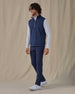 Men's Carson Vest in New Indigo, on model side view full length styled over a white long sleeve top with navy pants and white golf shoes