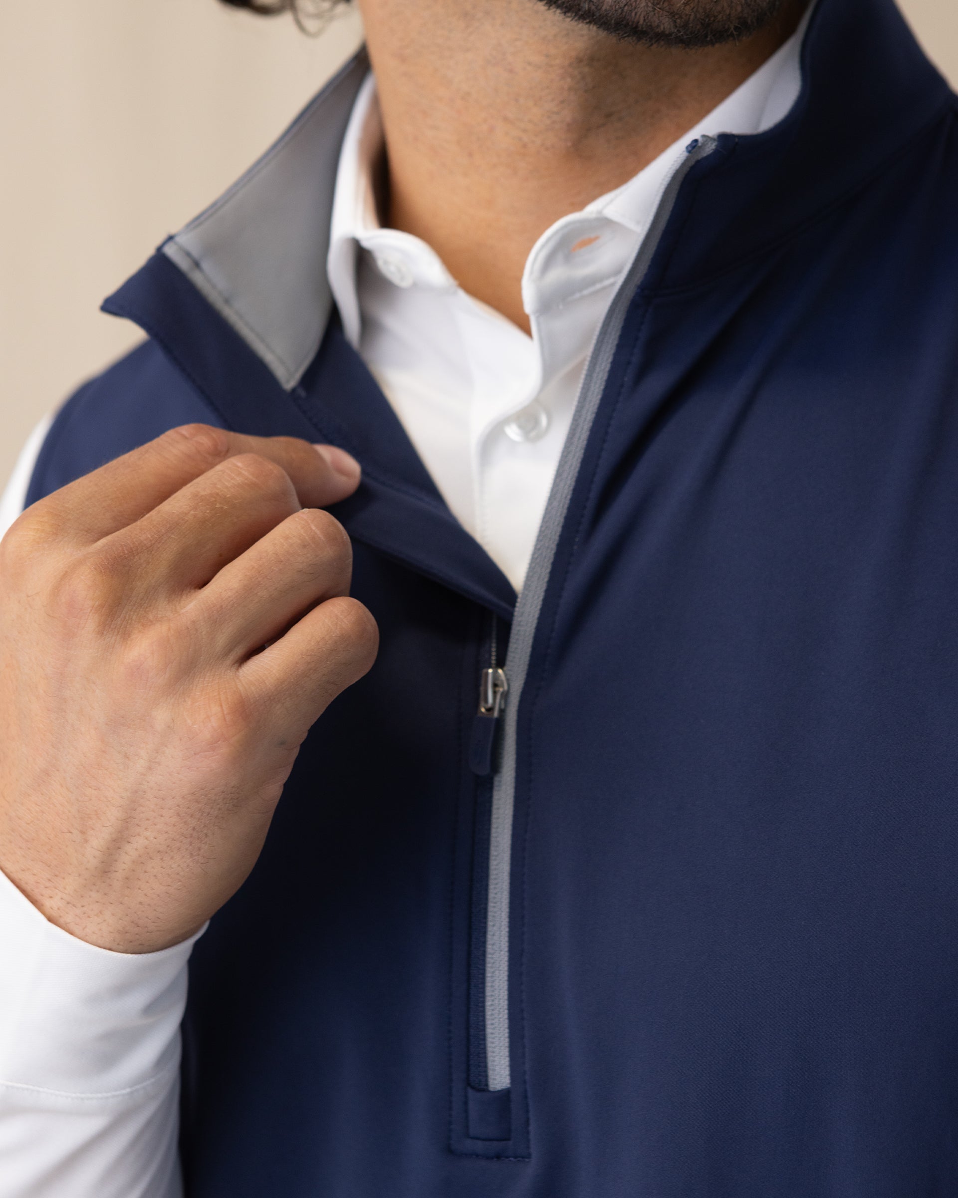 Men's Carson Vest in New Indigo, on model close-up view of the grey collar interior and quarter zip detail layered over a white polo
