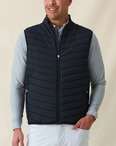 Men's Delta 2.0 Quilted Hybrid Vest in Black, front view on model featuring a black quilted front panel with full zip closure, layered over a gray long sleeve shirt, paired with white pants