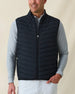 Men's Delta 2.0 Quilted Hybrid Vest in Black, front view on model featuring a black quilted front panel with full zip closure, layered over a gray long sleeve shirt, paired with white pants