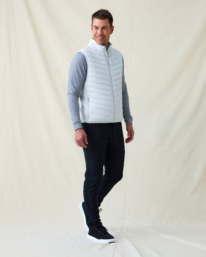 Men's Delta 2.0 Quilted Hybrid Vest in Silver, full length side view on model featuring a light silver quilted front panel with full zip closure, layered over a gray long sleeve shirt, paired with navy pants and black shoes