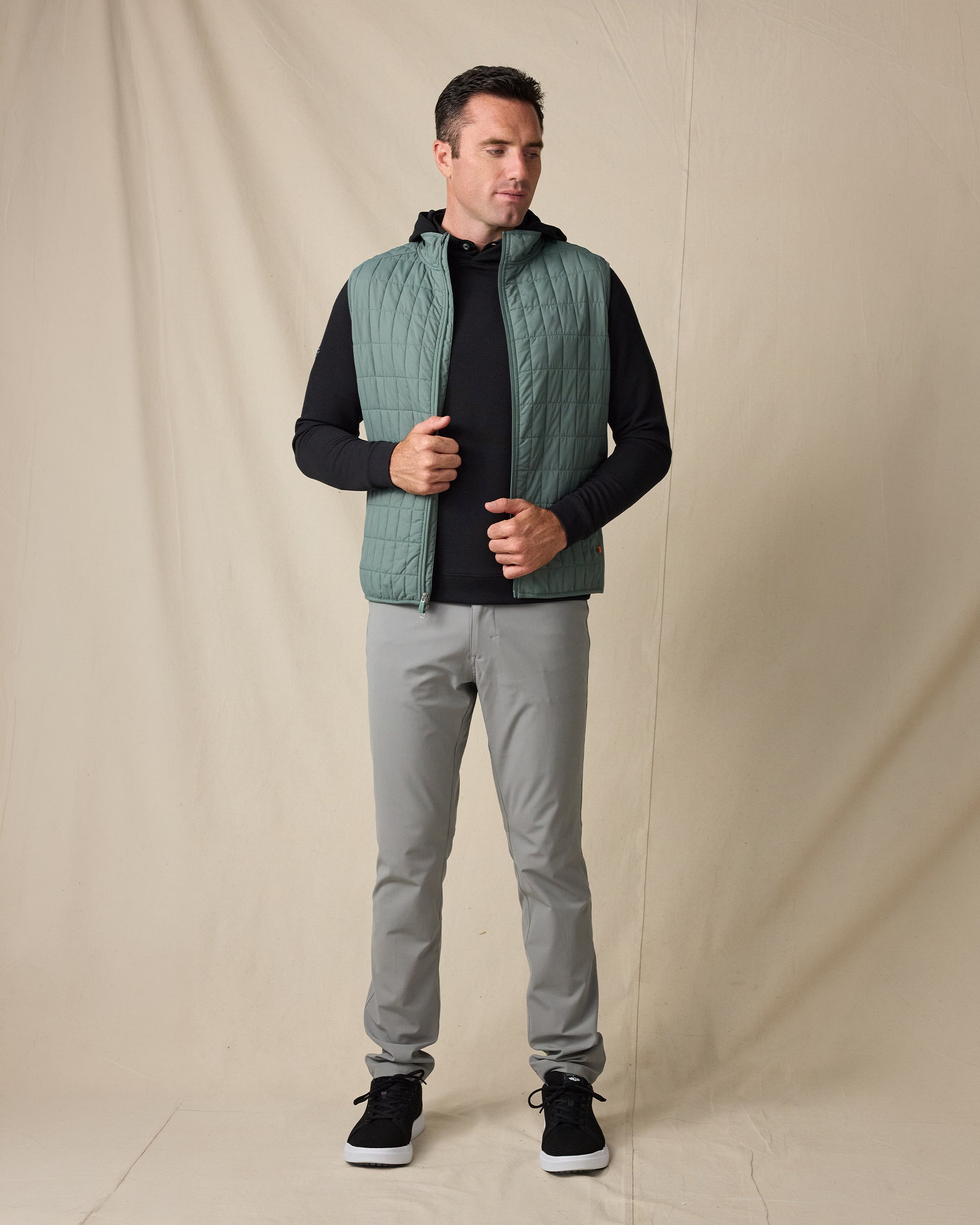 Model wearing the Big Horn Vest in Dark Forest over a black hoodie with gray pants and black sneakers.