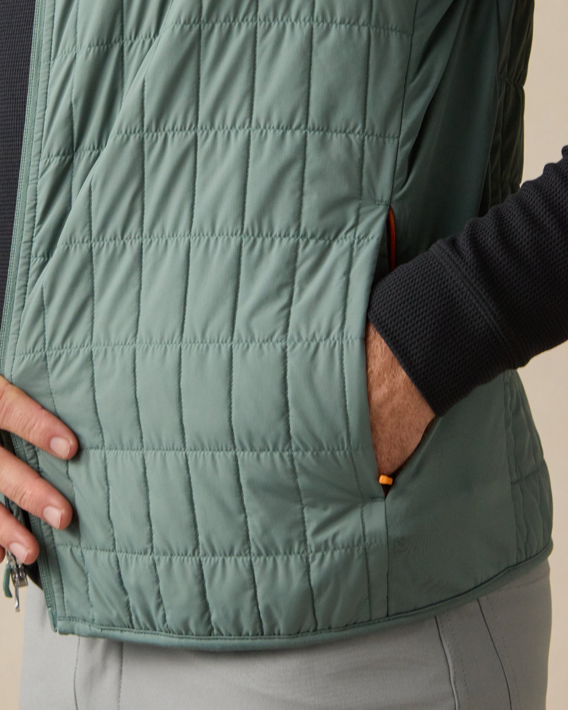 Close-up of the Big Horn Quilted Vest in Dark Forest, highlighting the grid quilting and zippered hand pocket with orange accents.