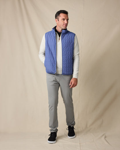 Model wearing the Big Horn Vest in Moonlight layered over a light quarter zip with gray pants and black sneakers.