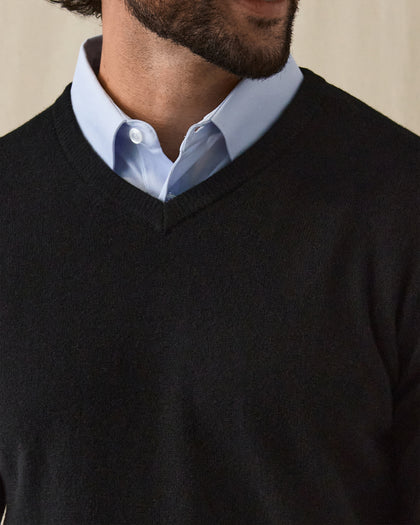 Men's Ballesteros V-Neck Sweater in Black, on model front close-up view featuring v-neck detail and fine knit texture worn over a light blue polo