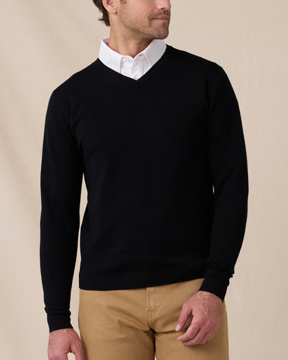 Man wearing the black Connery V-Neck Sweater layered over a white collared shirt with tan pants.