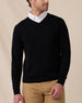 Man wearing the black Connery V-Neck Sweater layered over a white collared shirt with tan pants.