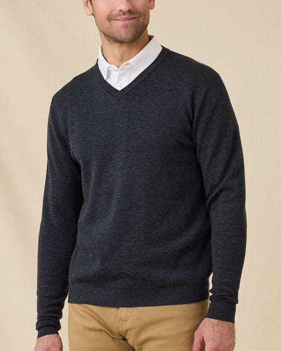 Man wearing the Dark Grey Heather Connery V-Neck Sweater layered over a white collared shirt with tan pants.