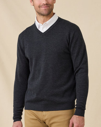 Man wearing the Dark Grey Heather Connery V-Neck Sweater layered over a white collared shirt with tan pants.