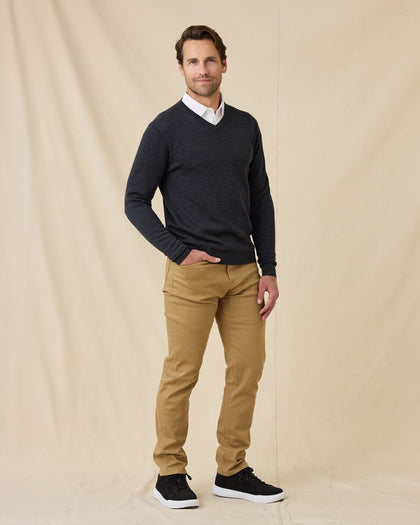 Man wearing the Dark Grey Heather Connery V-Neck Sweater over a white collared shirt, paired with tan pants and black sneakers.