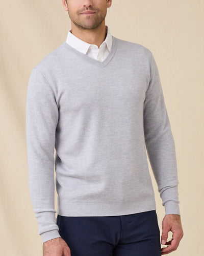 Man wearing the Light Grey Connery V-Neck Sweater layered over a white collared shirt with navy pants.