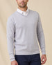 Man wearing the Light Grey Connery V-Neck Sweater layered over a white collared shirt with navy pants.