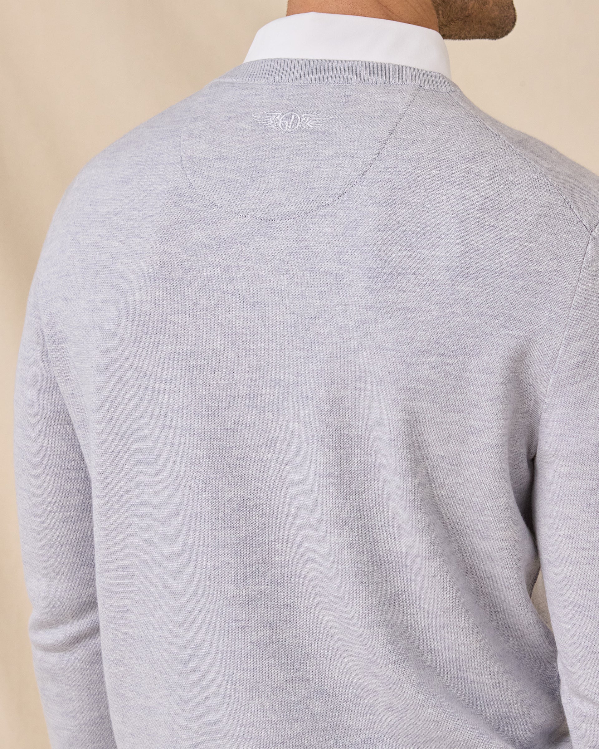 Close-up of the Light Grey Connery V-Neck Sweater showing the embroidered logo and seam detail below the back collar.