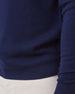 Close-up of a navy blue knit sweater worn with white pants, showing the ribbed hem and sleeve cuff.