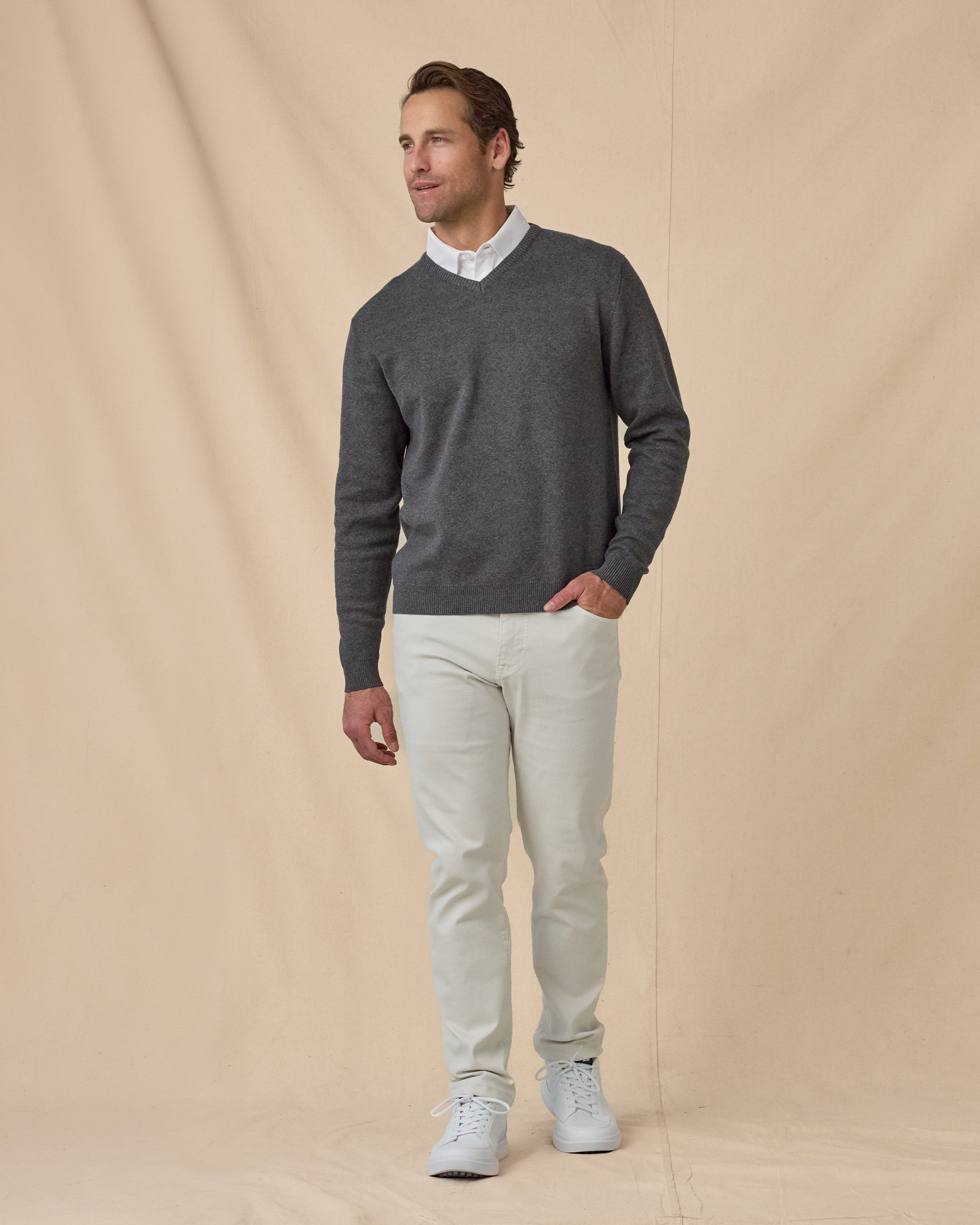 Wallace V-Neck Sweater in Dark Grey Heather with white pants, full outfit view layered over white polo and styled with light pants