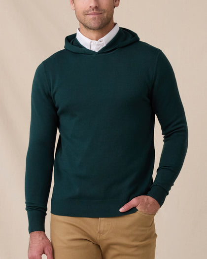 Model wearing the Crenshaw Reversible Sweater Hoodie in Dark Forest over a white polo, showing the solid green knit and hooded design.
