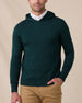 Model wearing the Crenshaw Reversible Sweater Hoodie in Dark Forest over a white polo, showing the solid green knit and hooded design.