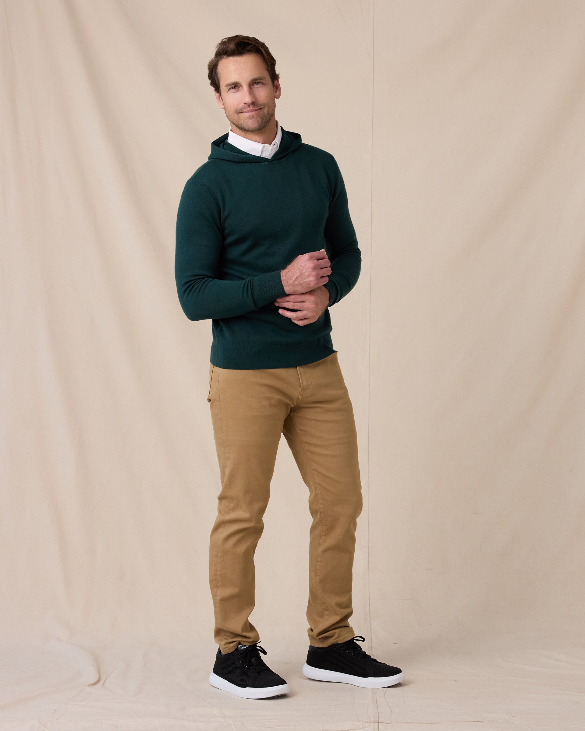 Model wearing the Crenshaw Reversible Sweater Hoodie in Dark Forest with tan pants and black sneakers.