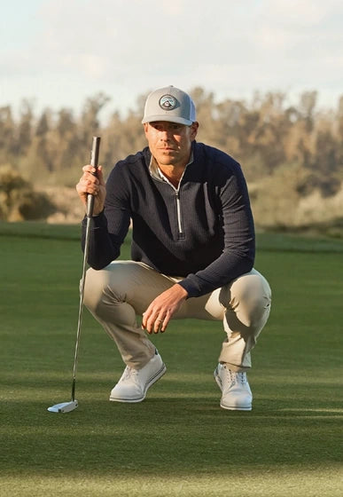 Golfer in Optic Quarter Zip and khaki pants crouching on the green with putter, Father's Day gift guide lifestyle image
